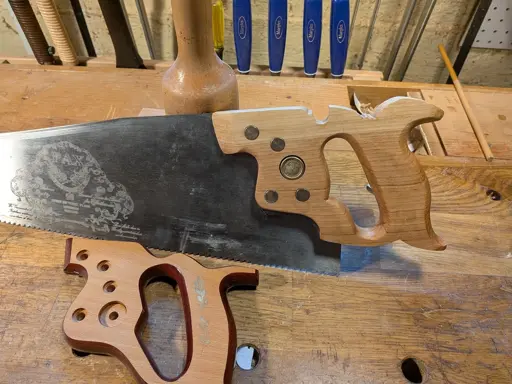 A panel saw with a vintage-looking handle and the stock handle it replaced.