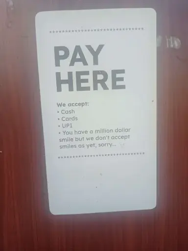 A sign saying: "PAY HERE"

"We accept:
1. Cash
2. Cards
3. UPI

You have a million dollar smile but we don't accept smiles as yet, sorry."