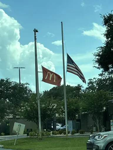 McDonald's and Burgerland flags at half mast near the entrance of a McDonald's drive through.
