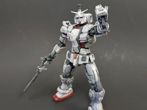 The HG Gundam EX in a standing pose with its right hand holding its rifle and its left reaching toward the beam sabers on its back