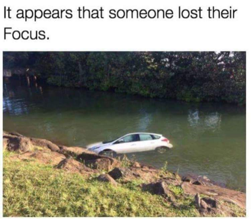 A white Ford Focus car barely floating above water level with caption above the picture "It appears that someone lost their Focus"